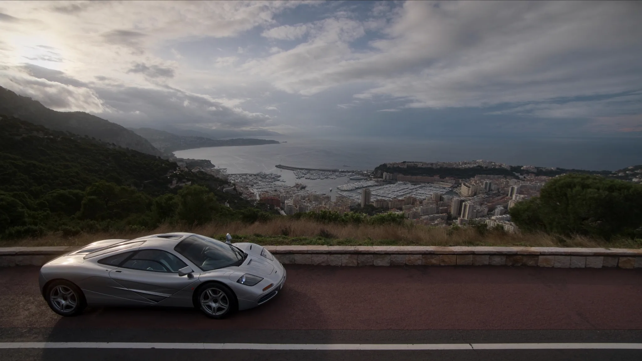 A silver McLaren F1 on the Moyenne Corniche with the whole principality far below
